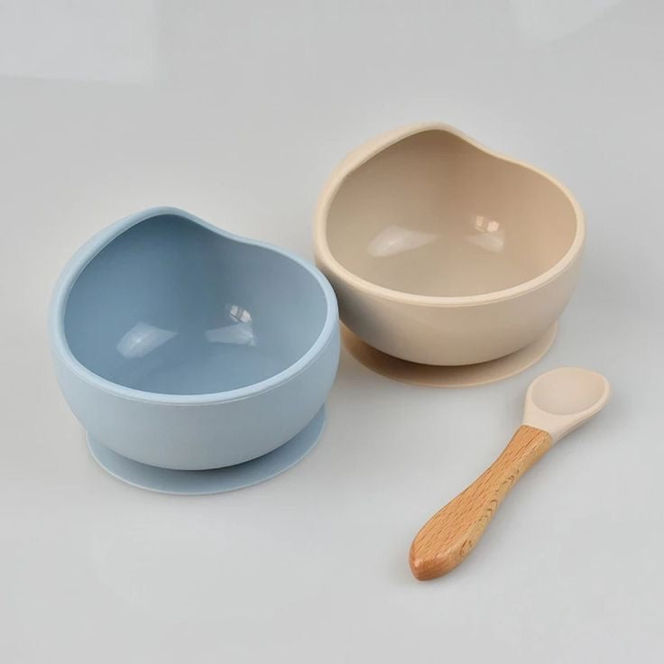 Présentation de deux bol pour enfants antidérapant de couleur bleu et beige avec une cuillère en bois et un embout en silicone de couleur beige.