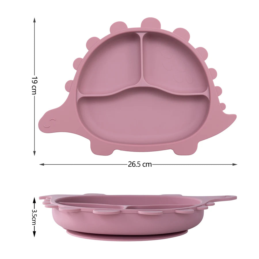 Présentation de la taille d'une assiette pour bébé en silicone rose en forme de dinosaure, avec les dimensions indiquées : 26,5 cm de largeur et 19 cm de hauteur.