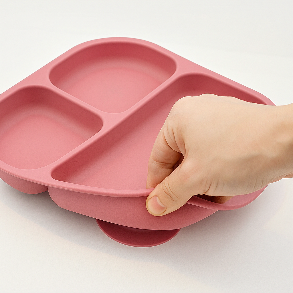 Présentation d’une démonstration d’une assiette à plusieurs compartiments qui est flexible et qui est de couleur rose.