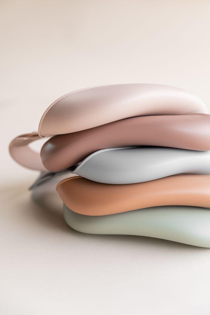 Présentation d'un ensemble de cinq bavoirs pour bébé empilés de différentes couleurs pastel.