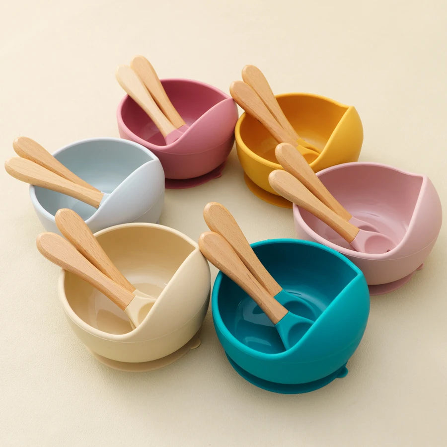 Présentation d'un ensemble de bols pour bébé avec des cuillères en bois, de différentes couleurs.