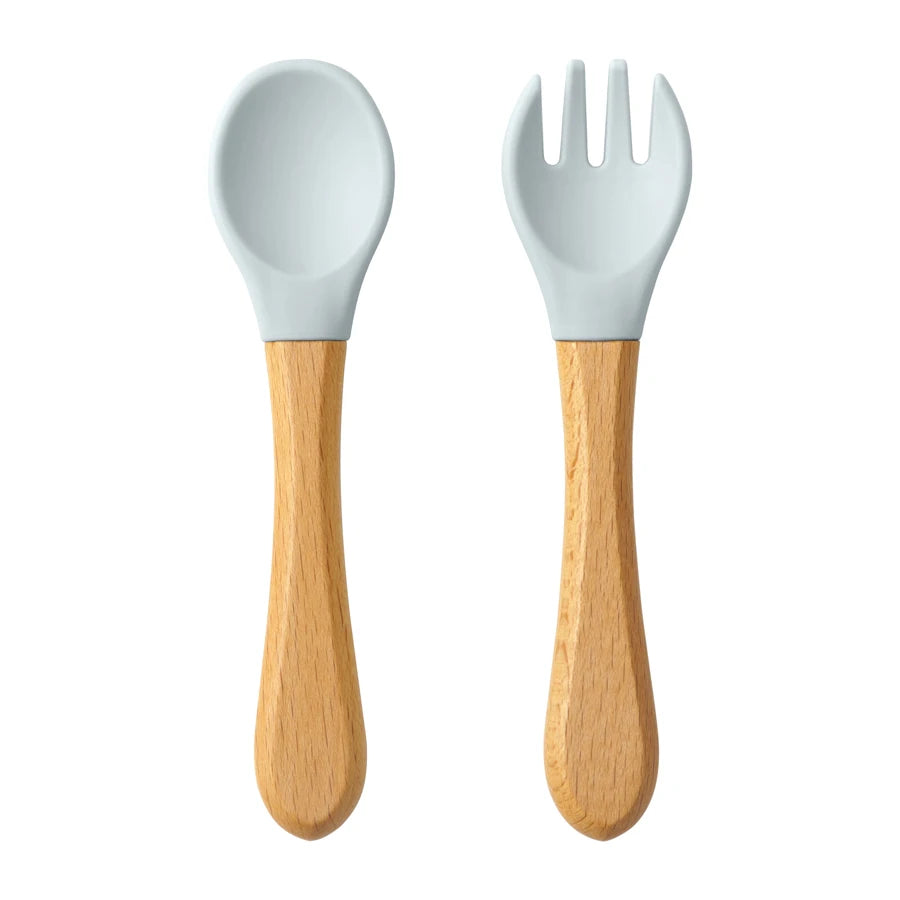 Présentation d’une fourchette et d’une cuillère pour bébé en bois avec des embouts silicone, bleu clair