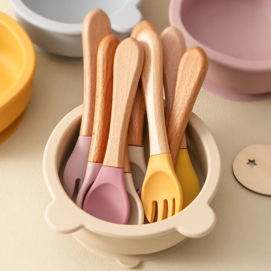 présentation de couverts pour bébé en bois Avec des embouts en silicone, coloré dans un bol, anti déversements avec oreilles d’ours beige. 