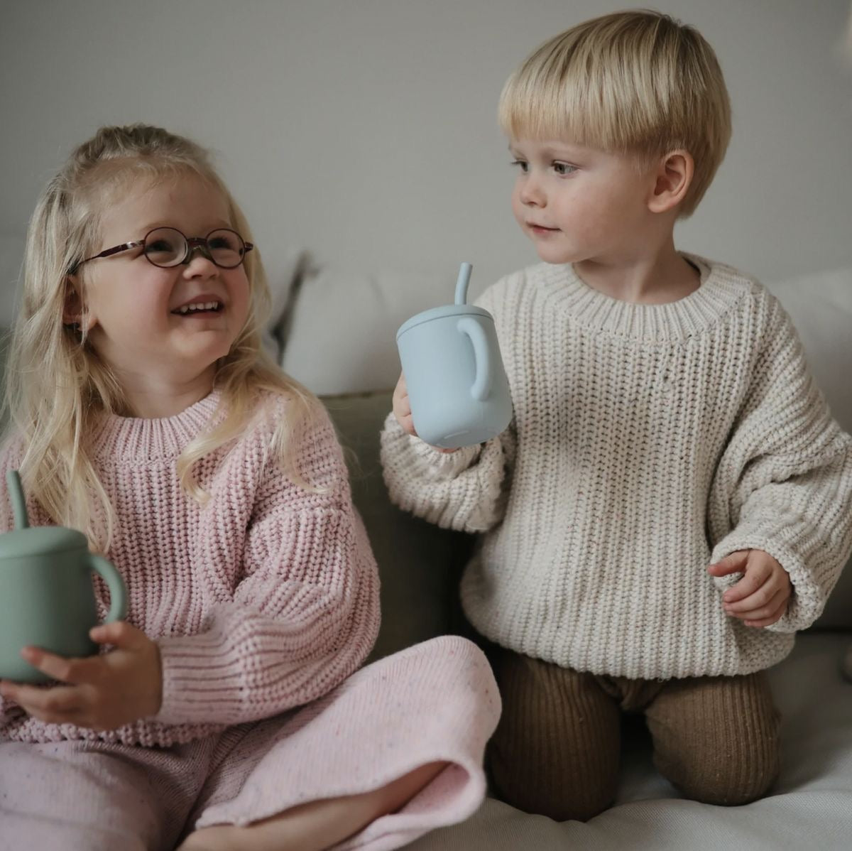Présentation de deux enfants une petite fille et un petit garçon qui sourie avec leur gobelet d’apprentissage 