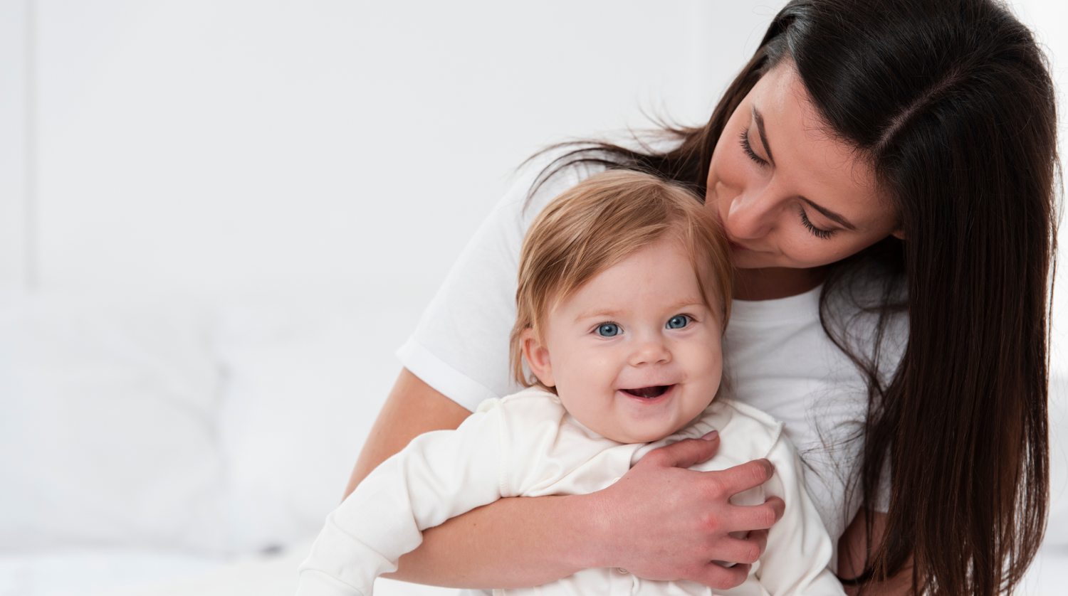 Portrait d’une mère et d’un enfant souriant, enlacé. Habiller en blanc tout les deux. 