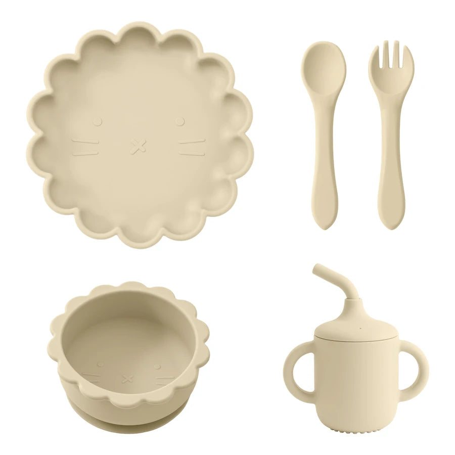Présentation d'une assiette, d'un bol, d'un gobelet et de couverts pour bébé en silicone beige.