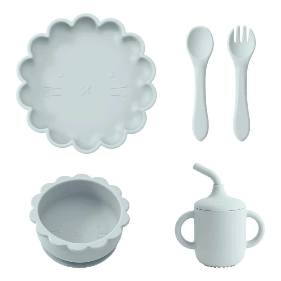 Présentation d'une assiette, d'un bol, d'un gobelet et de couverts pour bébé en silicone bleu clair.