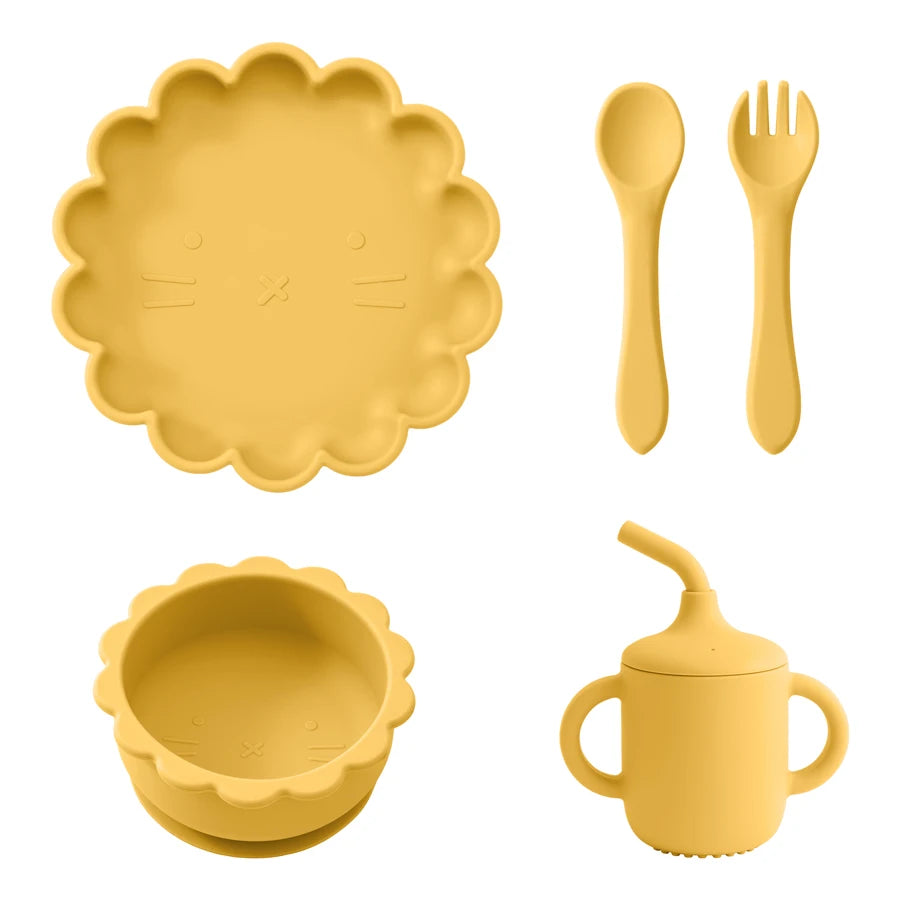 Présentation d'une assiette, d'un bol, d'un gobelet et de couverts pour bébé en silicone jaune.