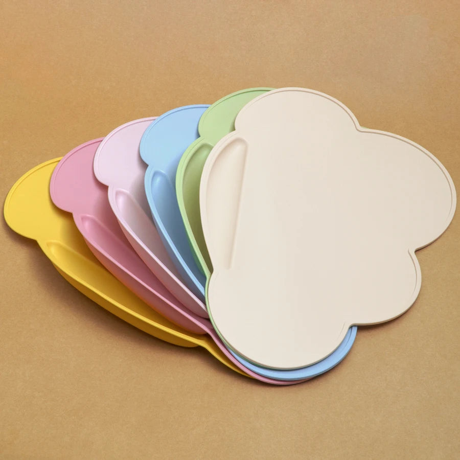 Présentation d'un ensemble de sets repas pour bébé en silicone de différentes couleurs, en forme de nuage, empilés les uns sur les autres.