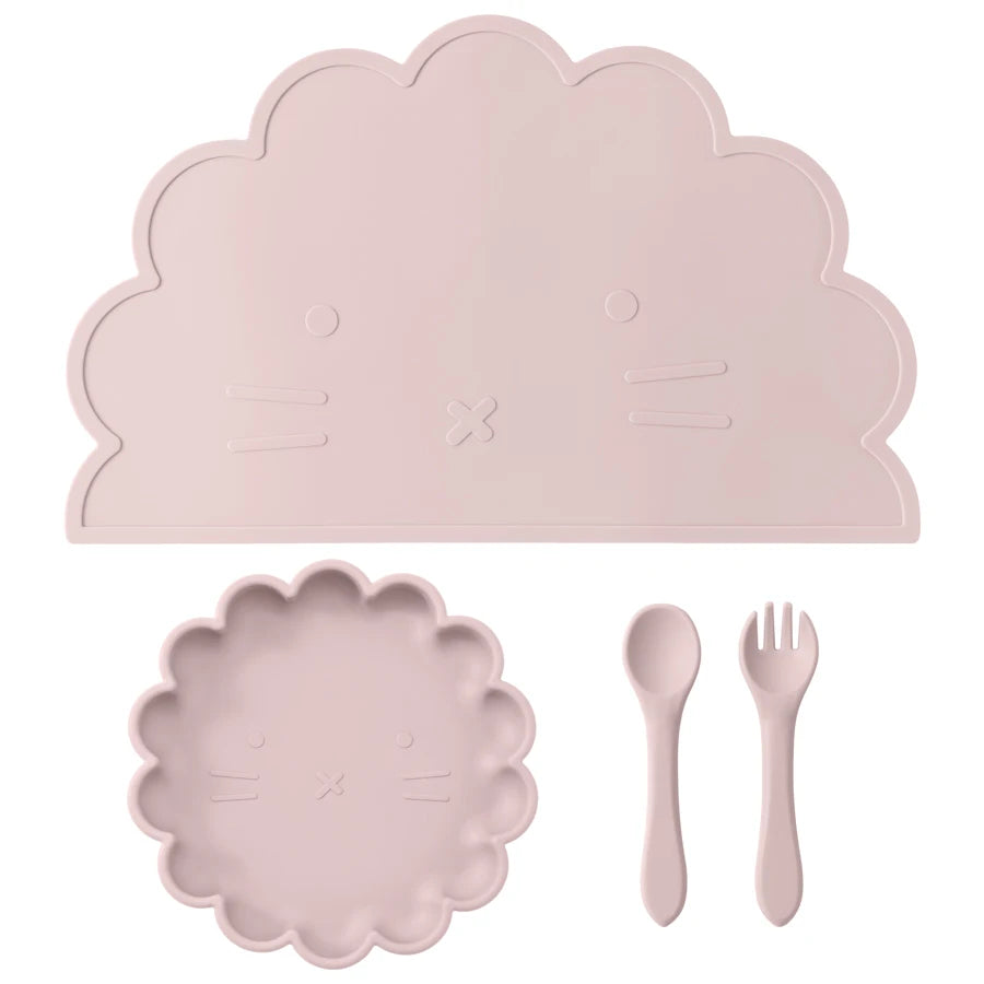 Présentation d'une assiette, un set de table et de couverts pour bébé en silicone rose clair, sur un fond blanc.