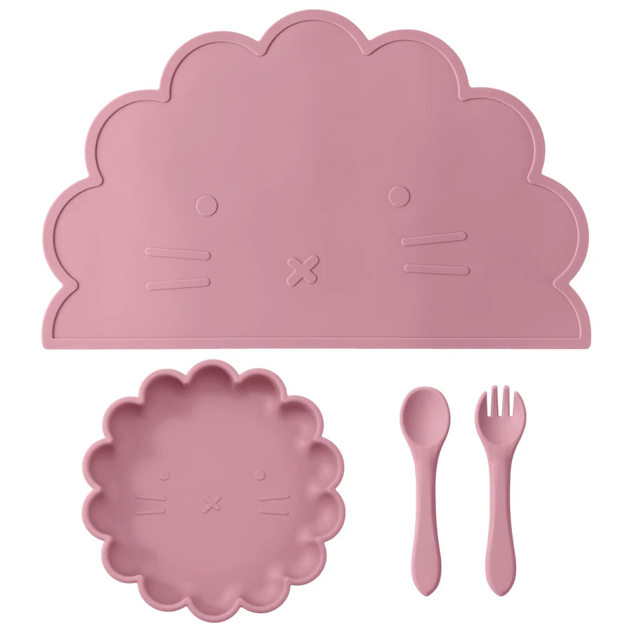 Présentation d'une assiette, un set de table et de couverts pour bébé en silicone rose foncé, sur un fond blanc.