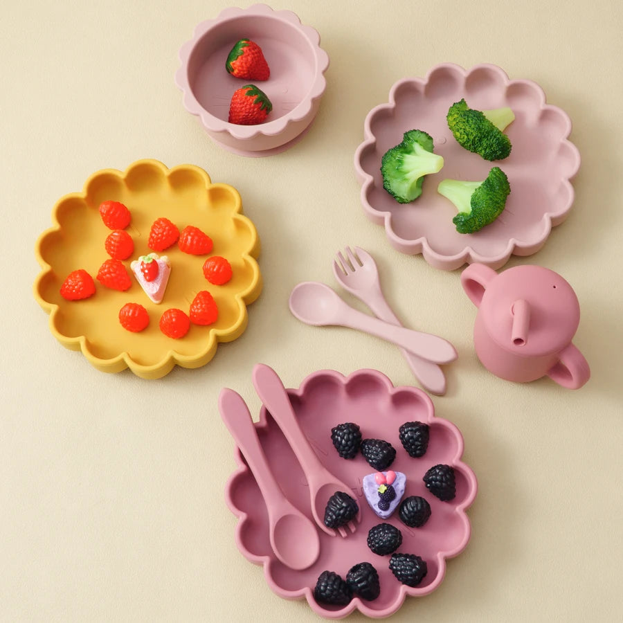 Présentation de quatre assiettes de couleurs différentes pour bébé en silicone avec des aliments variés.