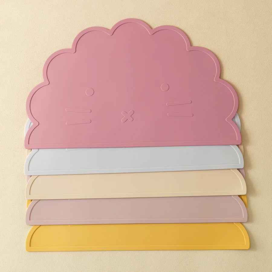 Présentation de sets de table pour bébé en silicone dans des couleurs différentes, empilés (rose foncé, bleu clair, beige, rose clair, jaune).