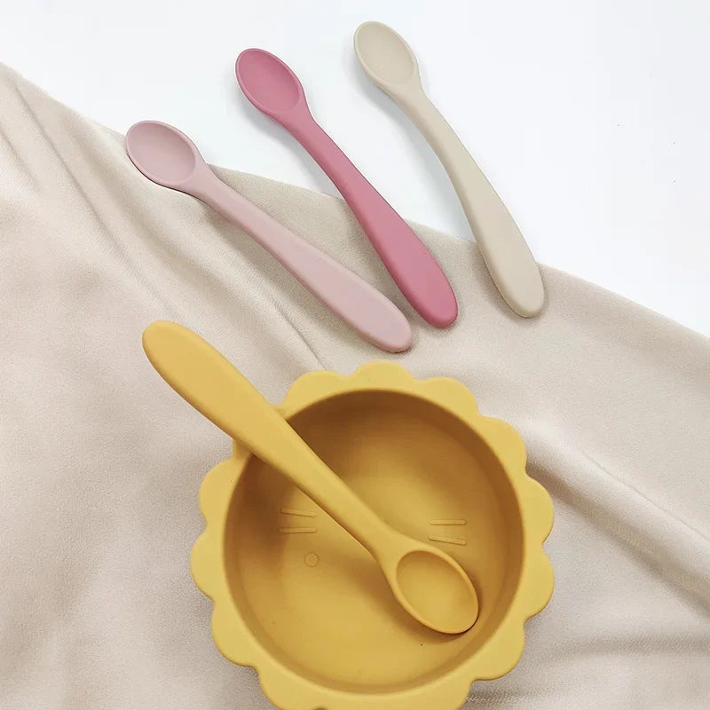 présentation de différentes cuillère en silicone avec un bol jaune pour bébé.
