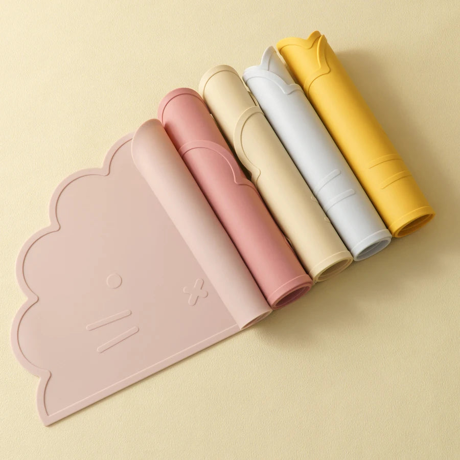 Présentation de sets de table pour bébé en silicone dans une gamme de couleurs différentes, un à plat et les autres roulés.