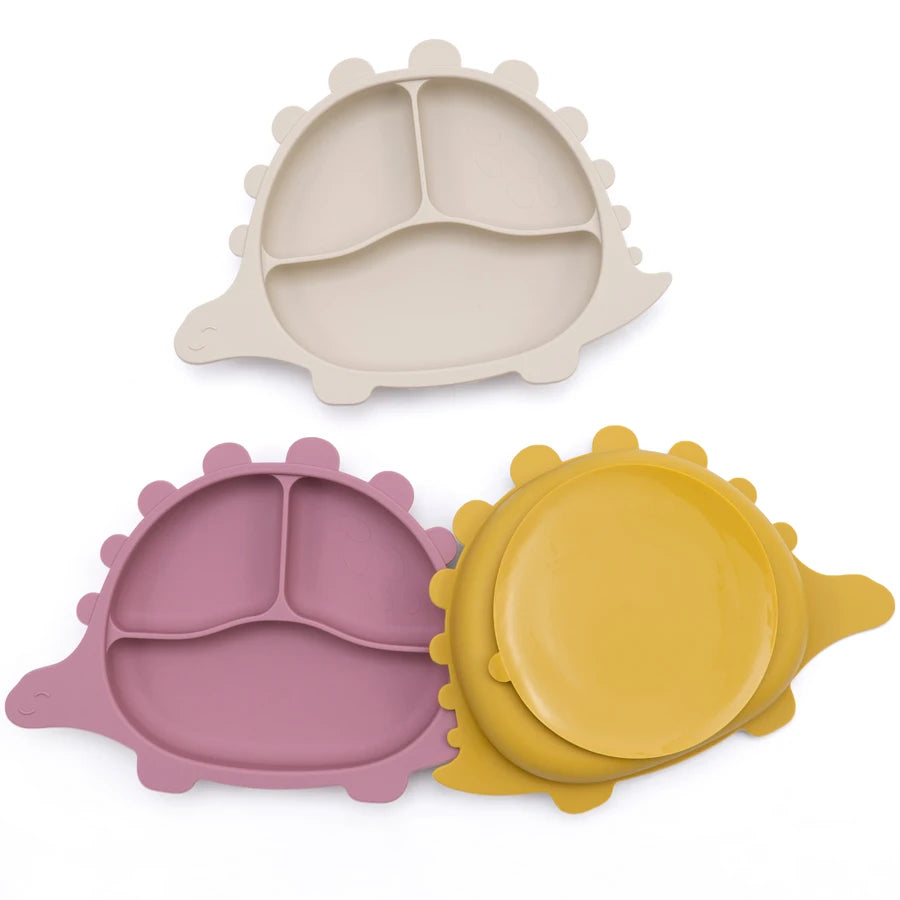 Présentation d'un ensemble de trois assiettes pour bébé en silicone en forme de dinosaure, de couleurs variées et avec des compartiments.